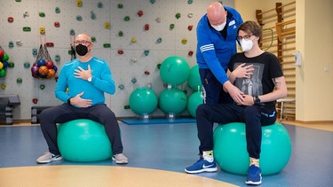 Zwei Patienten auf Gymnastikbällen mit Therapeut beim Atemtraining | Bild: picture alliance/dpa/Friso Gentsch