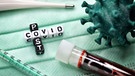 Buchstabenwürfel bilden den Schriftzug Post Covid neben Blutprobe und Coronavirus-Modell | Bild: picture alliance / CHROMORANGE | Christian Ohde