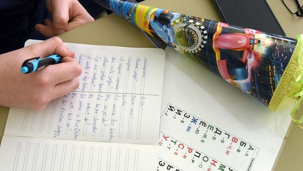 Eine Hand schreibt deutsch-ukrainische Wörter in ein Vokabelheft.  | Bild: dpa-Bildfunk/Waltraud Grubitzsch