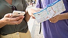Touristen mit Stadtplan und Handy (Symbolbild) | Bild: picture alliance / dpa-tmn | Christin Klose