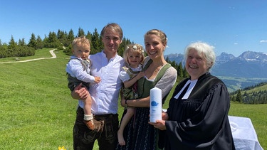 Stephan und Antonia Reindl mit ihren beiden Kindern auf dem Arm neben Pfarrerin Irene Conrad auf dem Wank. | Bild: BR/Astrid Uhr