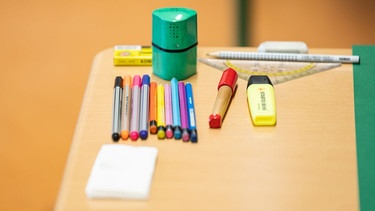 Verschiedene Stifte und Utensilien liegen auf einem Tisch in einem Klassenzimmer | Bild: picture alliance/dpa | Silas Stein