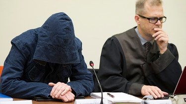  Der Angeklagte Carsten S. sitzt am 04.06.2013 im Gerichtssaal in München neben seinem Anwalt Jacob Hösl und verbirgt sein Gesicht hinter einer Kapuze. | Bild: picture-alliance/dpa