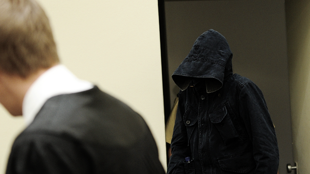 Der Angeklagte Carsten S. betritt versteckt unter einer Kapuzenjacke den Gerichtssaal. | Bild: picture-alliance/dpa