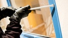  Ein als Einbrecher verkleideter Mann hebelt ein Fenster auf.  | Bild: picture-alliance/dpa/Daniel Bockwoldt