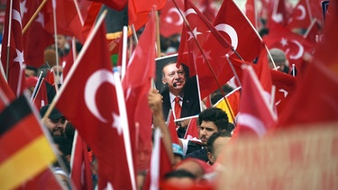 Anhänger des türkischen Staatspräsidenten Erdogan halten am 31.07.2016 in Köln Fahnen hoch. | Bild: dpa/Henning Kaiser