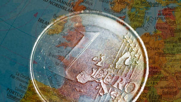 Eine Ein-Euro-Münze über Europa auf einem beleuchteten Globus  | Bild: picture-alliance/dpa