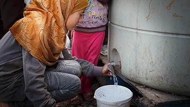 Eine junge Frau, die aus Syrien geflüchtet ist, zapft am 19.03.2015 im Flüchtlingslager der UNHCR in der Bekaa-Ebene im Libanon Wasser. | Bild: picture-alliance/dpa
