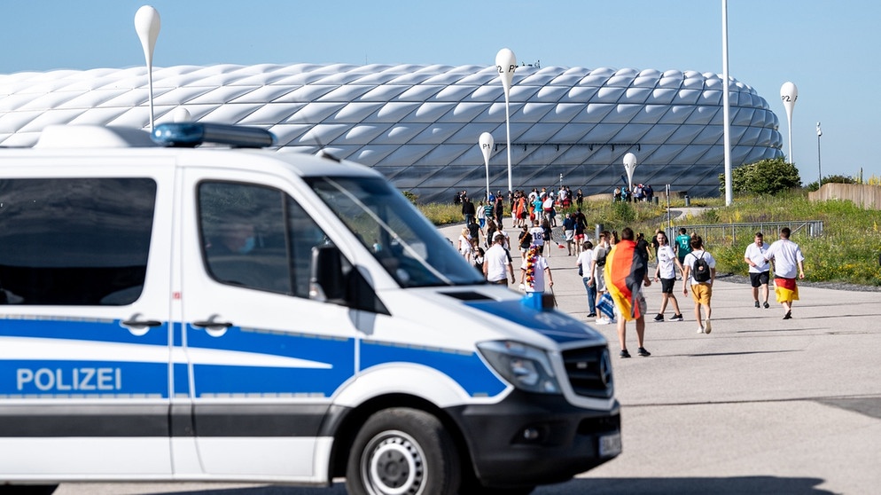 Ein Polizei-Fahrzeug fährt am Stadion und an Fußballfans vorbei.  | Bild: dpa-Bildfunk/Matthias Balk