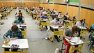 Abiturienten schreiben Prüfung in einer Turnhalle | Bild: picture-alliance/dpa/Armin Weigel