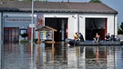 Mitglieder der Feuerwehr fahren am 08.06.2013 im Deggendorfer Ortsteil Fischerdorf im Hochwasser der Donau an ihrem Gerätehaus vorbei. | Bild: picture-alliance/dpa