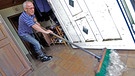 Hans Spranger schippt am 08.06.2013 im Deggendorfer Ortsteil Fischerdorf das Hochwasser der Donau aus seinem Haus. | Bild: picture-alliance/dpa