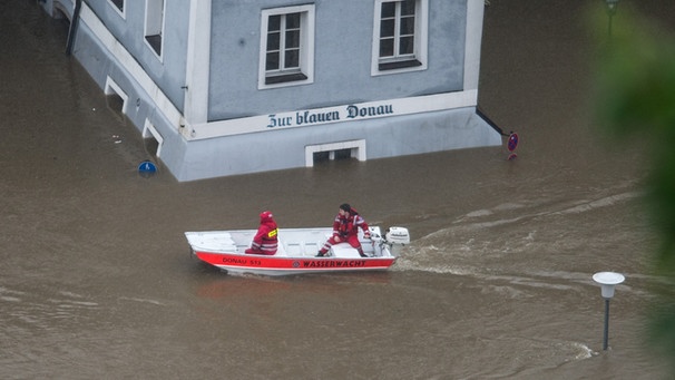Ein Boot der Wasserwacht fährt am 02.06.2013 in Passau (Bayern) im Hochwasser der Donau vor einem Haus vorbei, auf dem "Zur blauen Donau" steht. | Bild: picture-alliance/dpa