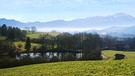 Symbolbild: Blick von einer Wiese über einen kleinen See auf das Karwendelgebirge im Morgendunst | Bild: picture-alliance/dpa/blickwinkel/S. Derder
