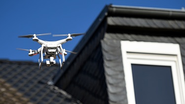 Eine Drohne schwebt vor dem Fenster eines Wohnhauses | Bild: picture-alliance/dpa/Henning Kaiser