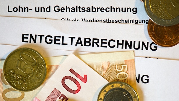 Auf Lohn- und Gehaltsabrechnungen (Entgeltabrechnungen) liegen Euromünzen und Eurogeldscheine. | Bild: picture-alliance/dpa