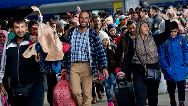 Flüchtlinge, die kurz zuvor mit einem Zug angekommen sind, jubeln am 06.09.2015 auf dem Hauptbahnhof in München (Bayern) auf einem Bahnsteig.  | Bild: dpa-Bildfunk