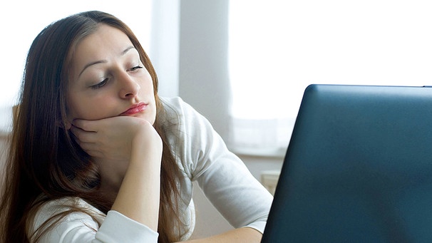 Symbolbild: Junge Frau im Büro blickt gelangweilt auf ihren Laptop | Bild: picture alliance/dpa/blickwinkel/allOver