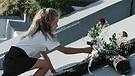 Ein deutsches Mädchen legt am Mahnmahl von Kalavrita (Griechenland) während einer Gedenkfeier am 27.07.2001 eine Rose nieder | Bild: picture-alliance/dpa