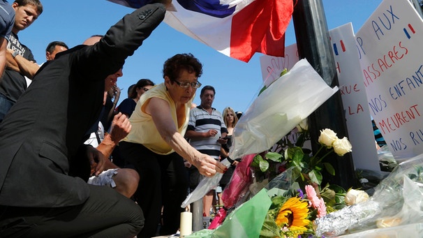 Eine Frau legt einen Blumenstrauß nieder in der Nähe des Unglücksorts an dem am Nationalfeiertag viele Passanten von einem Lastwagenfahrer getötet wurden. | Bild: Reuters (RNSP)/Pascal Rossignol