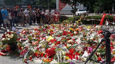 	Blumen und Kerzen liegen am 24.07.2016 vor dem Olympia-Einkaufszentrums, zwei Tage nach einer Schießerei mit Toten und Verletzten. | Bild: BR/Birgit Grundner