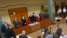 Die Zuhörer und die Prozessbeteiligten haben sich im Foyer des Landgerichts vor der Urteilsverkündung im Prozess gegen den früheren SS-Wachmann Reinhold Hanning am 17.06.2016 in Detmold erhoben.  | Bild: picture-alliance/dpa