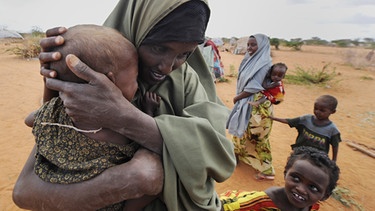 Ein Frau trägt im Flüchtlingslager Dadaab in Kenia ihr kleines Kind auf dem Arm. Kenias Regierung hat die Schließung des größten Flüchtlingslagers der Welt im Osten des Landes bis spätestens November angekündigt. | Bild: picture-alliance/dpa