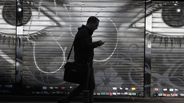 Ein Mann geht auf der Straße und schaut auf sein Smartphone (Archivbild) | Bild: picture-alliance/dpa
