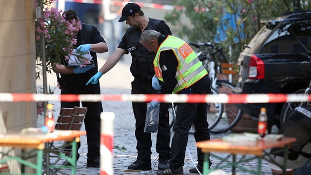  Ermittler der Polizei arbeiten am Tatort eines Bombenanschlags am 25.07.2016 in Ansbach (Bayern). Bei dem mutmaÃlich islamistisch motivierten Anschlag sind am Sonntagabend zwölf Menschen verletzt worden. Der mutmaßliche Täter sei ein 27-jähriger Flüchtling aus Syrien gewesen, sagte Innenminister Herrmann bei einer Pressekonferenz. Der junge Mann, der öfter in psychiatrischer Behandlung gewesen sei, wollte offensichtlich die Bombe mit scharfkantigen Metallteilen in seinem Rucksack bei einem Musikfestival mit etwa 2500 Besuchern zünden. Ihm wurde aber der Einlass verwehrt.  | Bild: dpa-Bildfunk/Daniel Karmann
