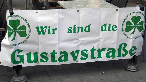 Weißes Plakat mit der grünen Aufschrift "Wir sind die Gustavstraße" an einem Tisch befestigt | Bild: BR-Studio Franken/ Alexander Loos