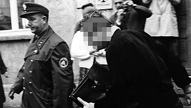 Der "Mittagsmörder" Klaus G. (M) flieht nach der Tatortbesichtigung in Neuhaus an der Pegnitz in der Oberpfalz am 11.09.1965 vor einer aufgebrachten Menschenmenge zum Polizeiauto. | Bild: picture-alliance/dpa