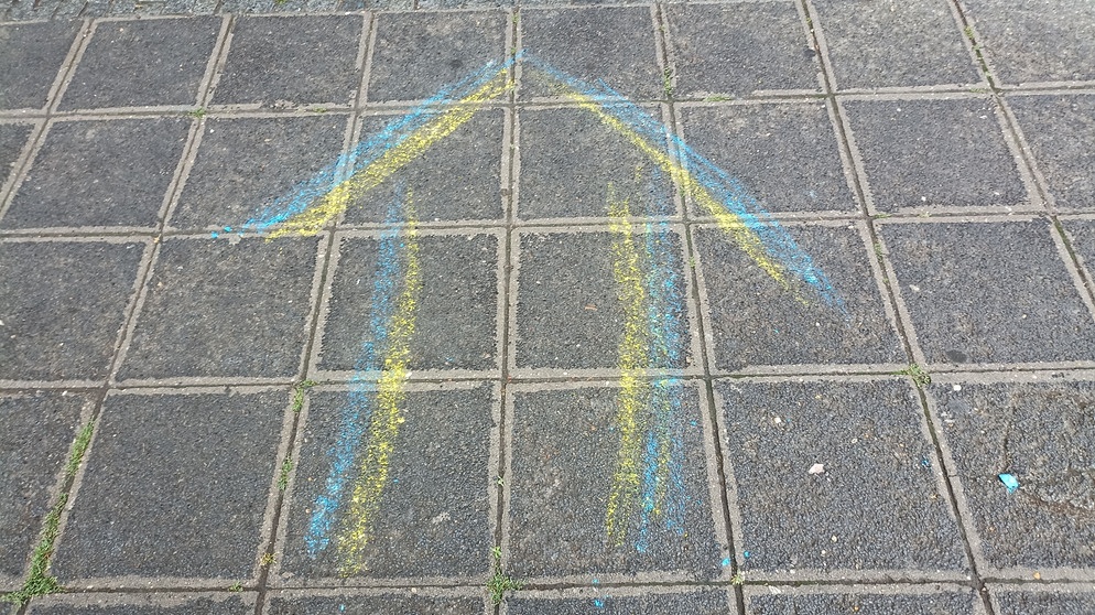 Blau-gelber Pfeil auf einem Bürgersteig. | Bild: BR/Eleonore Birkenstock