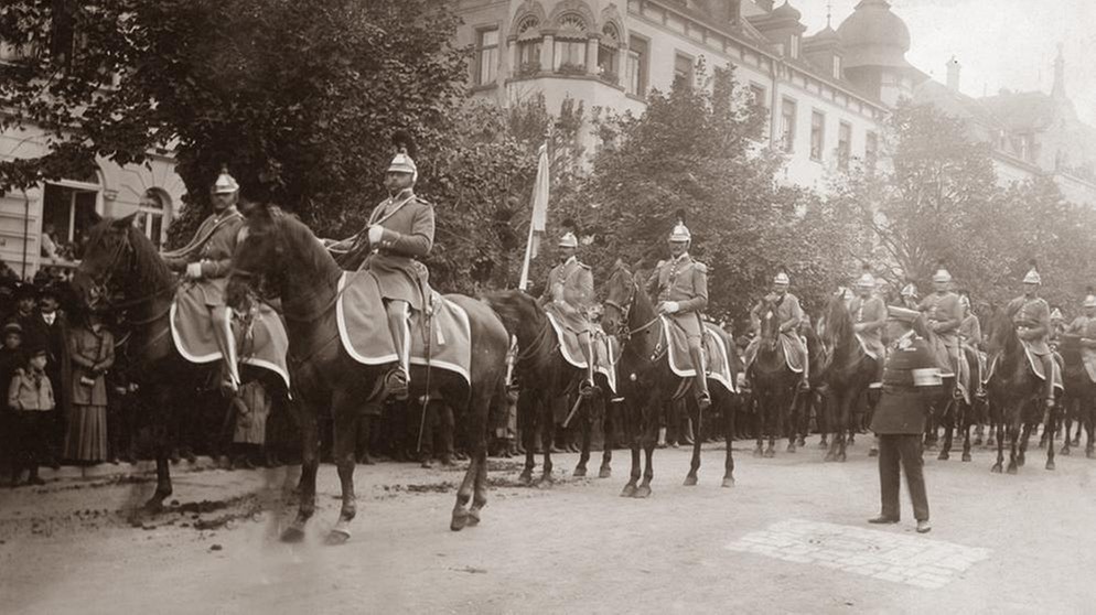Die Landwehrkavallerie reitet durch Münchens Straßen. Am Straßenrand stehen Menschen und beobachten den Zug (undatierte Aufnahme).  | Bild: SZ Photo
