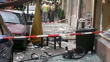 Nagelbombenattentat am 9. Juni 2004 in Köln: Glasscherben vor einem durch eine Explosion zerstörten Haus | Bild: picture-alliance/dpa