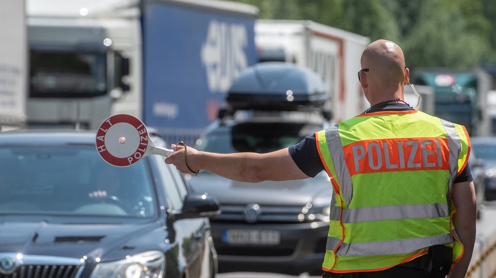 Ein Polizist steht mit einer Kelle an einer Kontrollstelle der Bundespolizei auf der Autobahn A3 kurz hinter der deutsch-österreichischen Grenze bei Pocking.   | Bild: dpa-Bildfunk/Armin Weigel
