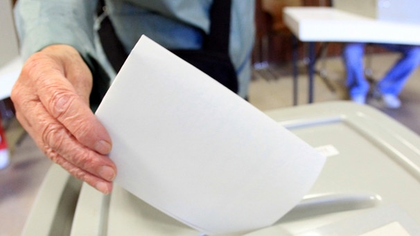 Symbolbild: Ein Stimmzettel wird in eine Wahlurne geworfen | Bild: picture-alliance/dpa