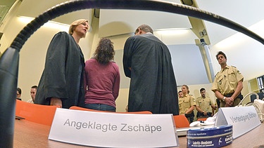 Die Angeklagte Beate Zschäpe (2.v.l.) steht am 06.08.2014 im Gerichtssaal in München (Bayern) zwischen ihren Anwälten Anja Sturm (l) und Wolfgang Heer (3.v.l.). Vor dem Oberlandesgericht wurde der Prozess um die Morde und Terroranschläge des NSU fortgesetzt | Bild: picture-alliance/dpa