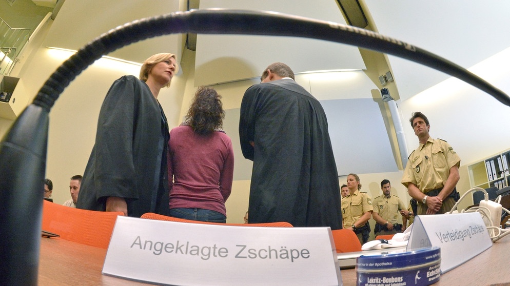 Die Angeklagte Beate Zschäpe (2.v.l.) steht am 06.08.2014 im Gerichtssaal in München (Bayern) zwischen ihren Anwälten Anja Sturm (l) und Wolfgang Heer (3.v.l.). Vor dem Oberlandesgericht wurde der Prozess um die Morde und Terroranschläge des NSU fortgesetzt | Bild: picture-alliance/dpa