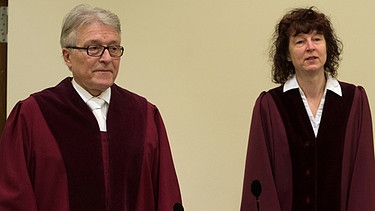 Bundesanwalt Herbert Diemer und die Oberstaatsanwältin Anette Greger stehen in ihren Roben im Gerichtssaal 101 des Oberlandesgericht in München an ihren Plätzen.  | Bild: picture-alliance/dpa