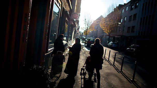 Der Ort des Nagelbombenanschlags, viele Jahre nach dem Attentat: die Keupstraße in Köln - 3 Menschen, nur schattenhaft erkennbar, stehen auf dem Gehsteig vor einem Laden | Bild: picture-alliance/dpa