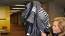 Der Zeuge Frank L., der mit einer Jacke sein Gesicht verdeckt, wird von einer Polizistin in den Gerichtssaal im Oberlandesgericht in München geführt | Bild: picture-alliance/dpa
