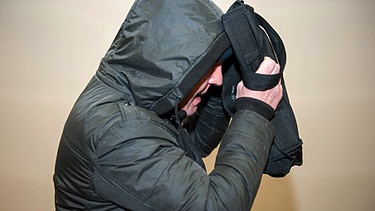Der Zeuge Andreas S. verlässt den Gerichtssaal im Oberlandesgericht München und hält dabei eine Tasche vor sein Gesicht | Bild: picture-alliance/dpa