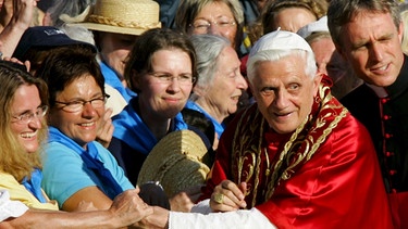 Papst Benedikt XVI. unterhält sich am 11. September 2006 auf dem Weg zur Altöttinger Basilika mit seinem Privatsekretär Georg Gänswein, während er die Hände Gläubiger schüttelt. | Bild: picture-alliance/dpa/Matthias Schrader