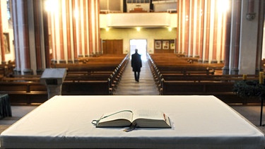 ILLUSTRATION - In dieser symbolisch nachgestellten Szene verlässt ein Mann am eine Kirche | Bild: picture-alliance/dpa/Ingo Wagner