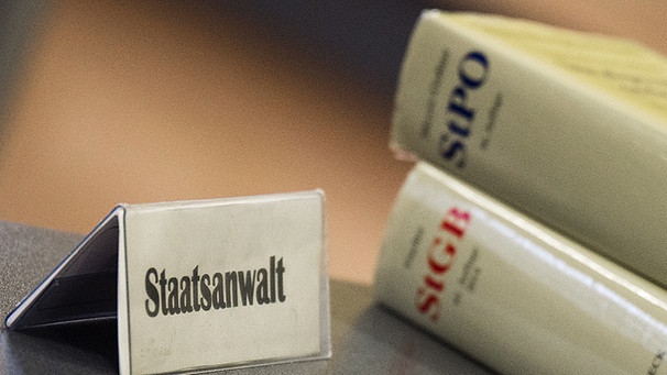 Symbolbild: Ein Schild mit der Aufschrift "Staatsanwalt" steht auf einem Tisch neben Gesetzesbüchern | Bild: picture-alliance/dpa/Armin Weigel