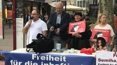 Cengiz Dogan (l.), Sprecher des Solidaritätskreises für Mesale Tolu, und seine Mitstreiter stehen am 25. April 2018 auf dem Münsterplatz in Ulm. | Bild: BR/Joseph Weidl