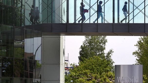 Menschen gehen auf einer Glasbrücke in der Zentrale der Weltbild Gruppe in Augsburg | Bild: picture-alliance/dpa