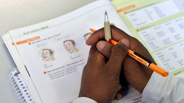 Sprachkurs für Flüchtlinge, gefaltete Hände mit Stift liegen auf einem Deutsch-Buch | Bild: picture-alliance/dpa/Hendrik Schmidt