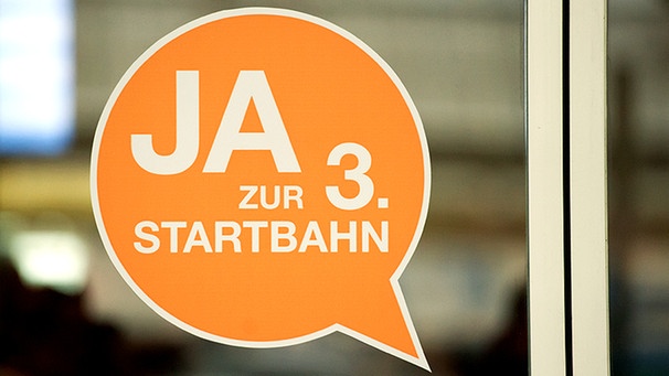 Ein Aufkleber mit der Aufschrift "Ja zur 3. Startbahn" klebt an einer Glastür | Bild: picture-alliance/dpa