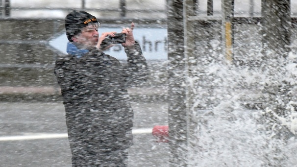 Mann fotografiert eine Flutwelle mit seinem Smartphone | Bild: picture-alliance/dpa